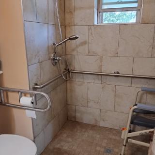 A well-equipped accessible bathroom with safety features such as handrails and a shower chair.
