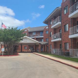 A view of a brick apartment building with balconies and an entrance drive.
