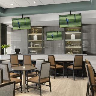 A modern bar and restaurant area with tables, chairs, and multiple TV screens.