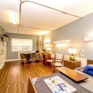 A well-lit hospital room featuring a patient bed and comfortable seating area.