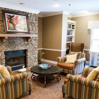 A cozy living room with a stone fireplace, armchairs, and a coffee table.