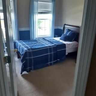 A cozy bedroom with a single bed and blue plaid bedding.