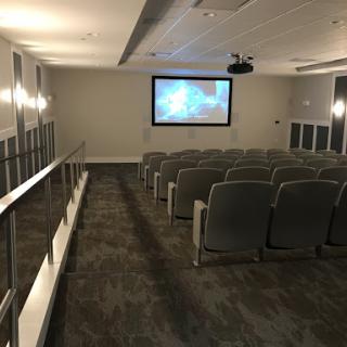 A modern auditorium setup featuring comfortable seating and a projection screen.