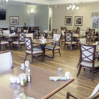 An empty dining room with neatly arranged tables and chairs, featuring elegant decor and soft lighting.