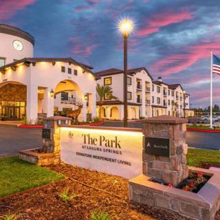 The exterior of a hotel building during sunset, with clear signage and surrounding landscape.