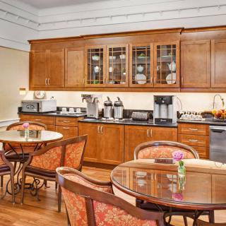 A cozy dining area with wooden cabinets and tables, featuring a coffee station.