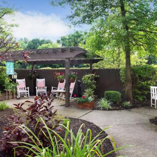 A serene garden patio with comfortable seating surrounded by lush greenery.