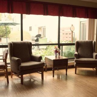 A cozy indoor seating area with armchairs and a view of the garden through large windows.