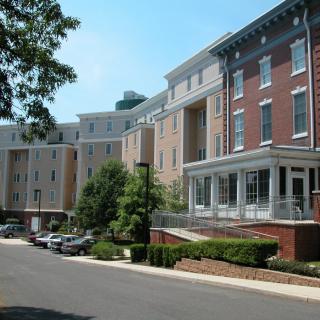 Residential buildings with a parking area and trees lining the street.