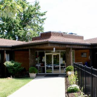 A modern architectural building with a welcoming entrance surrounded by greenery.