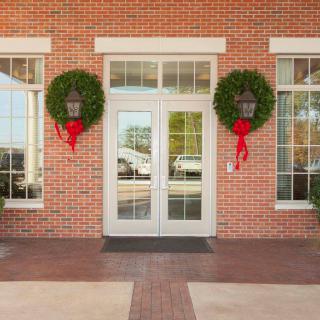 A festive brick building entrance decorated with wreaths and red ribbons.