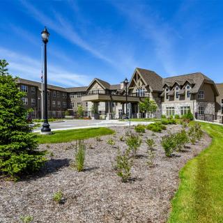 A large, elegant building surrounded by well-maintained landscaping under a clear blue sky.