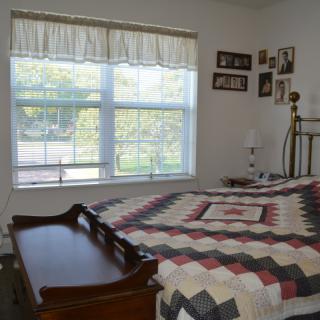A cozy bedroom with a quilt-covered bed and large window providing natural light.
