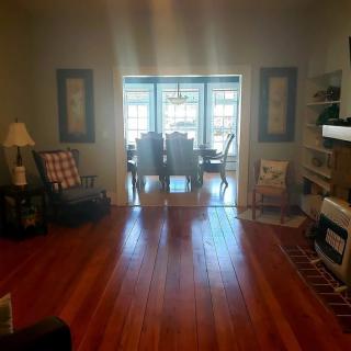 A cozy living room leading into a dining area with hardwood floors and stylish furniture.