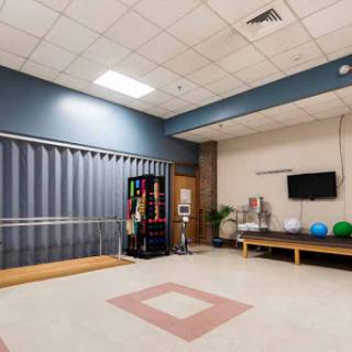 A spacious rehabilitation room equipped with therapy tools, exercise equipment, and a vending machine.
