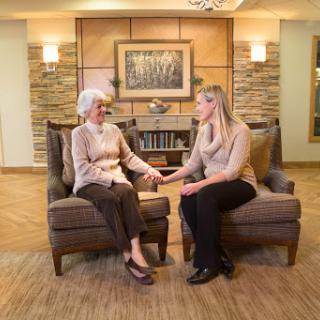A heartwarming moment between a caregiver and an elderly woman, sharing a conversation in a warm and inviting environment.