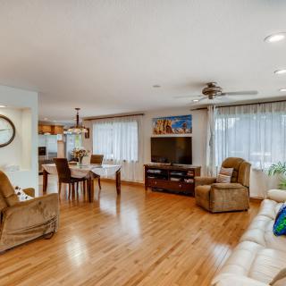 A cozy living and dining space with hardwood floors, featuring comfortable seating and a large television.