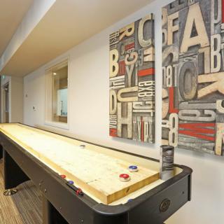 An indoor game room featuring a shuffleboard table and decorative wall art.