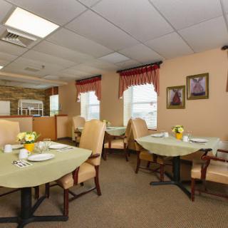 A cozy dining area featuring round tables set for meals, adorned with fresh flowers and framed artwork.