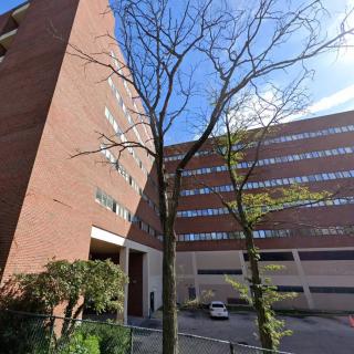 A view of a modern urban building with trees in the foreground and a clear sky above.