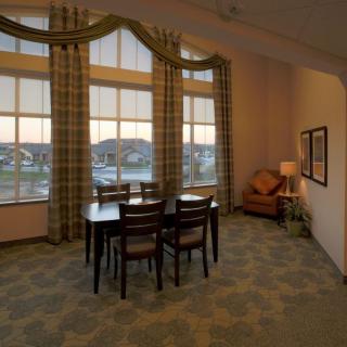 A cozy dining room with a wooden table, chairs, and large windows adorned with curtains.