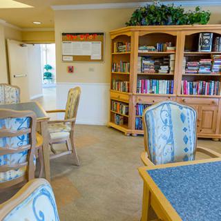 A cozy reading room with bookshelves, tables, and chairs.