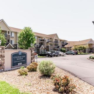 A residential apartment complex with a parking lot and landscaping.