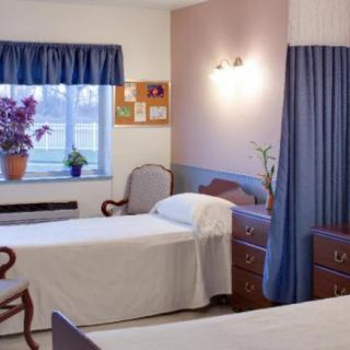 A tidy bedroom with two single beds, featuring blue curtains and a cozy ambiance.