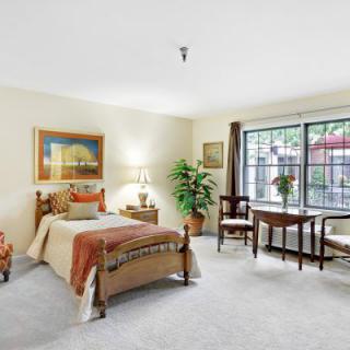 A cozy bedroom with a single bed, large window, and elegant furnishings.