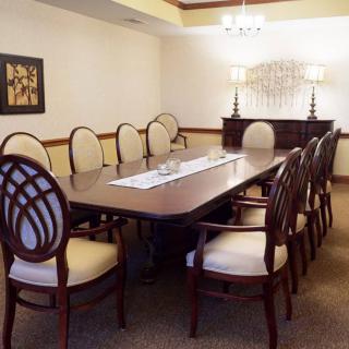 A neatly arranged conference room with a long table and upholstered chairs.
