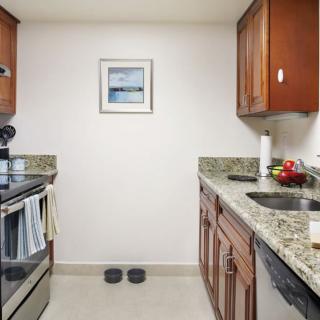A modern kitchen with wooden cabinets, granite countertops, and stainless steel appliances.