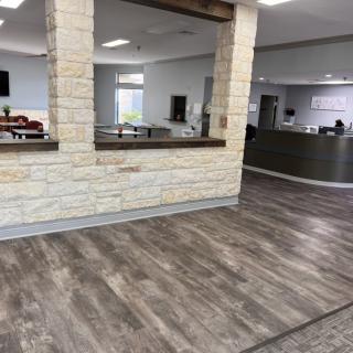 A modern office reception area with stone accents and wooden flooring.