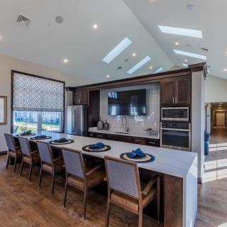 A modern kitchen interior featuring a spacious island with barstools, sleek appliances, and abundant natural lighting.