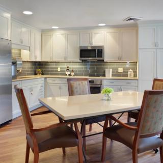 A modern kitchen with a dining area featuring a table and chairs, stainless steel appliances, and stylish cabinetry.