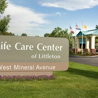Entrance to the Life Care Center of Littleton with a welcoming sign and flags.
