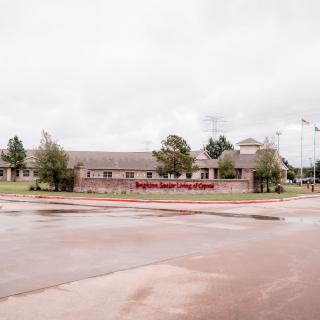 Image of a school building on a cloudy day with a view of the parking lot and surrounding trees.