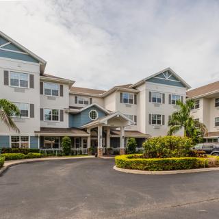 A multi-story residential building with landscaped surroundings and palm trees.