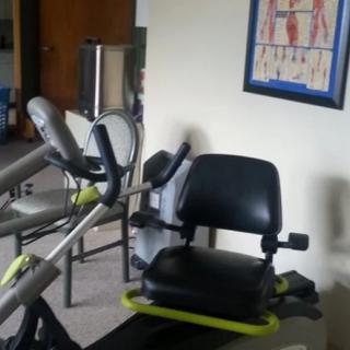 A gym room featuring exercise equipment and a poster of human anatomy on the wall.