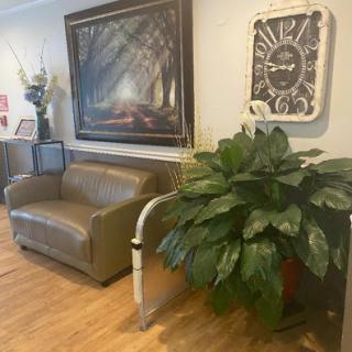 A cozy living room space featuring a leather sofa, decorative plant, and artwork on the wall.