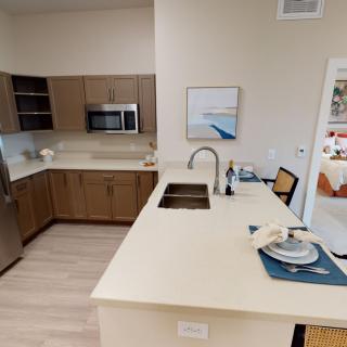 A modern kitchen with sleek countertops, stainless steel appliances, and a small dining setup.