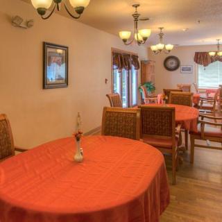 A cozy dining room setup with orange tablecloths and elegant chandeliers.