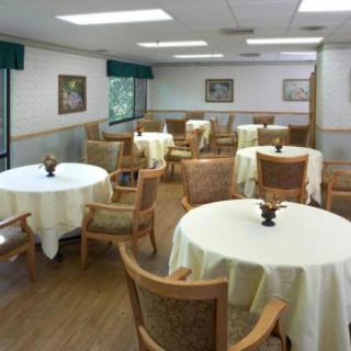 A neatly arranged dining area with round tables covered in tablecloths and wooden chairs.