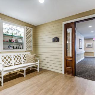 A cozy hallway with a decorative bench and open doorway leading to another room.