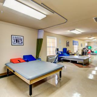 A spacious therapy room equipped with beds and exercise equipment, designed for rehabilitation purposes.