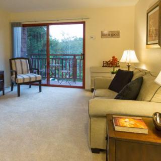 A cozy living room with a comfortable sofa, soft lighting, and a sliding door leading to a balcony.