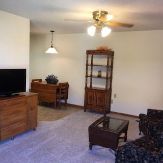 A cozy living room featuring a TV, a wooden cabinet, and comfortable seating.