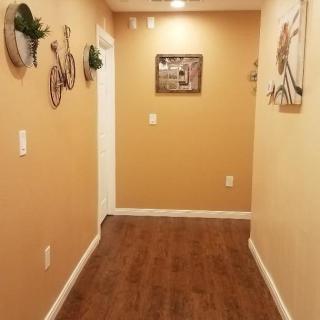 A warmly lit hallway with wooden flooring and decorative items on the walls.