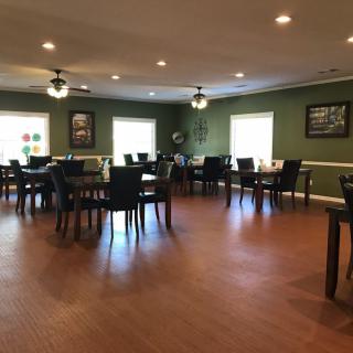 An empty dining area with neatly arranged tables and chairs on a wooden floor.