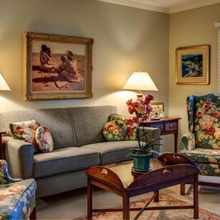 A cozy living room featuring a sofa adorned with decorative pillows, two side lamps, and artwork on the walls.