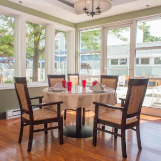 A cozy dining area with a round table set for four, surrounded by windows and natural light.